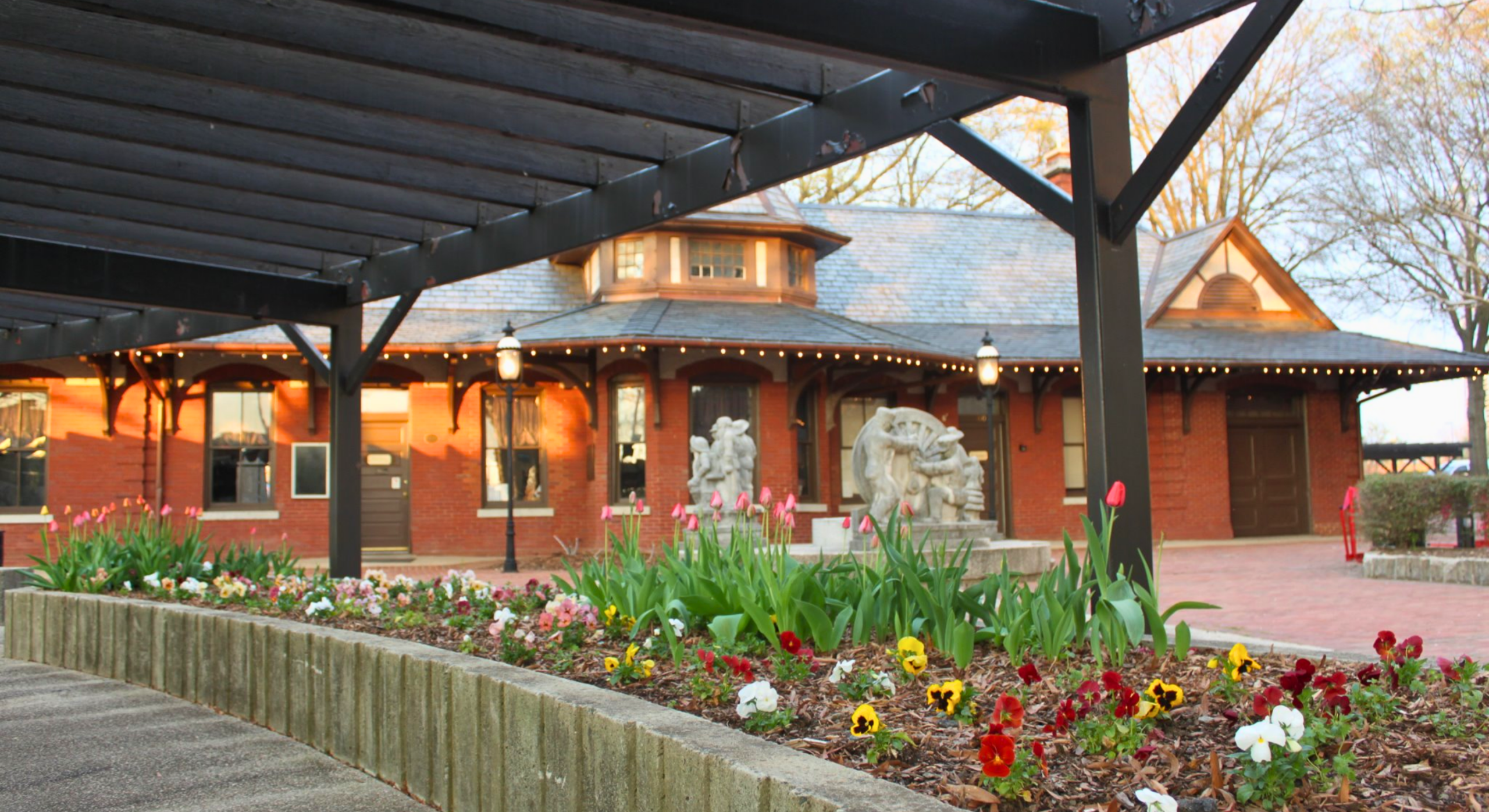 the Historic Depot in downtown Burlington showing a brick building with pretty landscaping and a brick walkway.