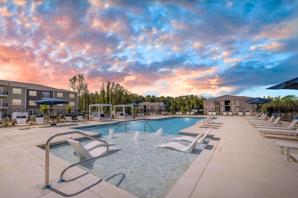 Resort-style pool with sun shelf loungers at Preston Park Apartments.
