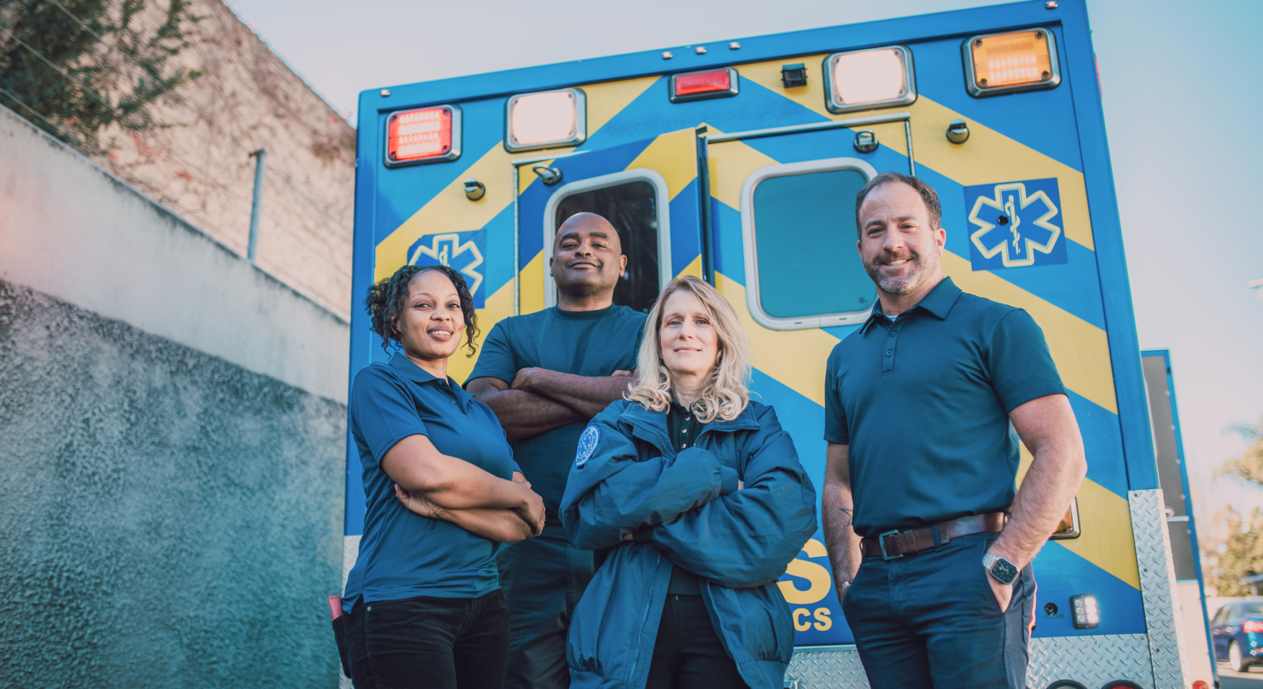 Group of emergency medical services professionals standing together in front of an ambulance.