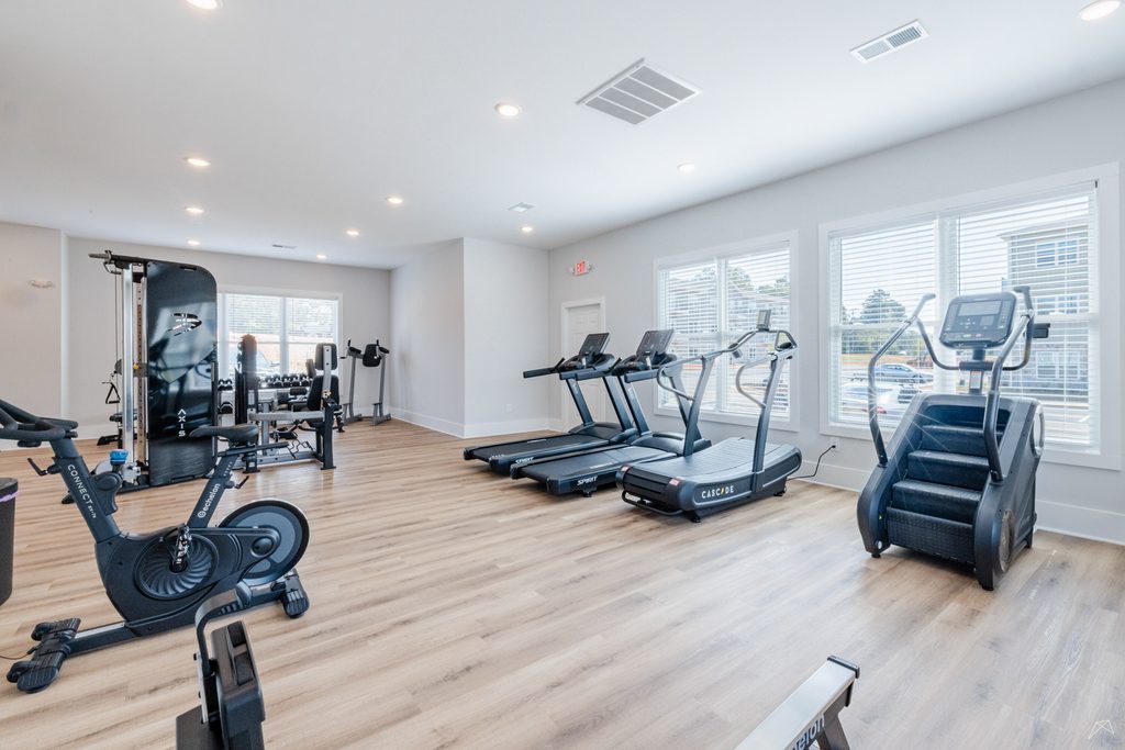 Bright fitness center at Preston Park Apartments in Burlington, NC, with treadmills, cardio equipment, and stationary bikes.
